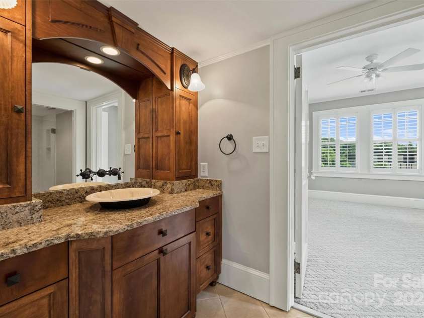 215 Main Street, Belmont, NC 28012.  MLS# CAR4134774, YatesRealty ID 22545. One of two 2nd floor bathrooms with custom wood cabinetry, granite countertop, built in hamper, vessel sink and  wall mounted faucet.  The arch mirror has built in light and separate wall scones.  The shower and commode are 