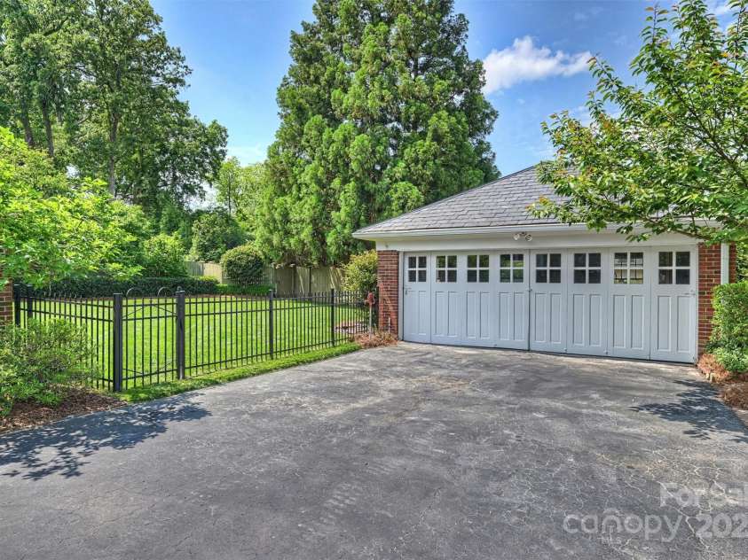 215 Main Street, Belmont, NC 28012.  MLS# CAR4134774, YatesRealty ID 22545. Original 1928 Carriage house style garage with slate roof and fully retracting garage doors that open all the way into the garage.  Concrete floor was replaced in 2024.  Back yard is completely fenced.  Separate water pipe f