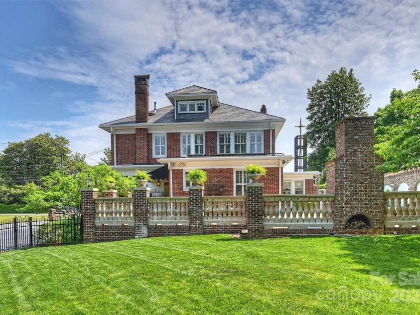 215 Main Street, Belmont, NC 28012.  MLS# CAR4134774, YatesRealty ID 22545. Rear view of the house and terrace featuring concrete balustrade system with brick columns and outdoor fireplace with arched firewood storage in the back. The brick columns has a pipe running up for irrigation. Three of thes