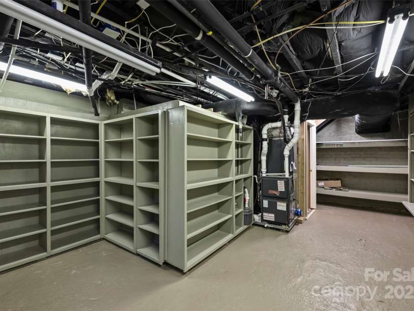 215 Main Street, Belmont, NC 28012.  MLS# CAR4134774, YatesRealty ID 22545. The basement utility room is just off the wine room and features great shelving and bright lighting.  The furnace in this area was replaced in 2022 along with the AC.  The floor is concrete and there is french drain system i