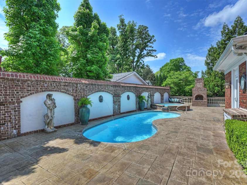 215 Main Street, Belmont, NC 28012.  MLS# CAR4134774, YatesRealty ID 22545. The Kidney shaped fiberglass salt water pool is heated and has a heated spa with a waterfall into the pool.  The A wonderful wood burning outdoor fireplace add to the charm of this oversized Terrace.  Wood box in located in 