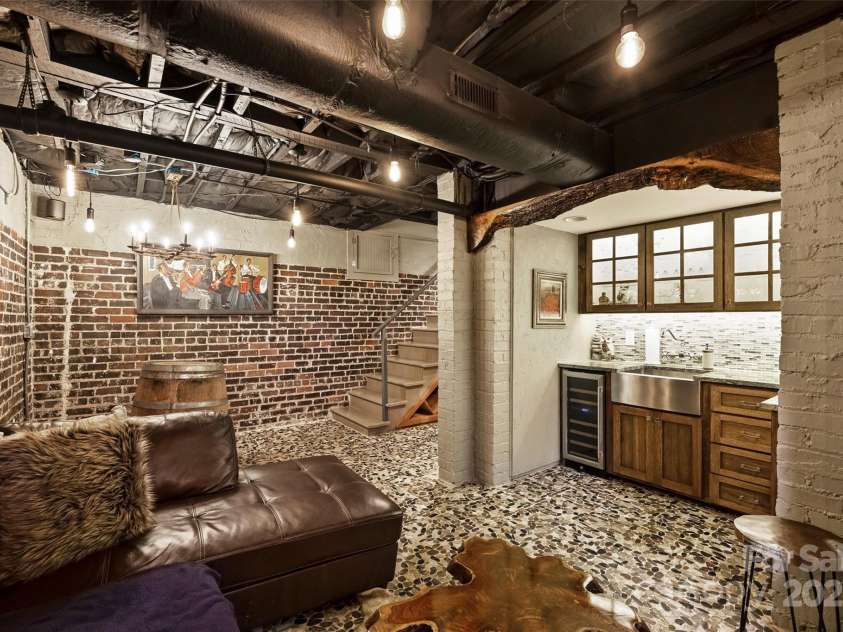 215 Main Street, Belmont, NC 28012.  MLS# CAR4134774, YatesRealty ID 22545. The main part of the basement has been transformed into a Napa inspired wine room with kitchenette that features a stainless farm sink and wine cooler.  The mosaic stone tile floor adds interest along with beautiful live edg