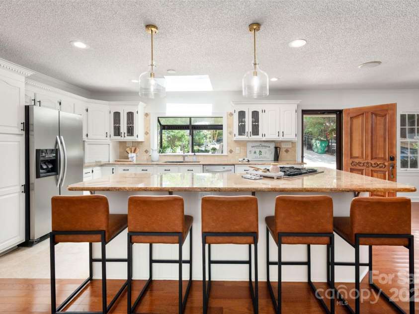 6259 River Cabin Lane, Charlotte, NC 28278.  MLS# CAR4271955, YatesRealty ID 22576. Stunning kitchen featuring a skylight, travertine floors and backsplash, stainless steel appliances, a gas stove, LED recessed lighting, and an oversized island—perfect for entertaining!