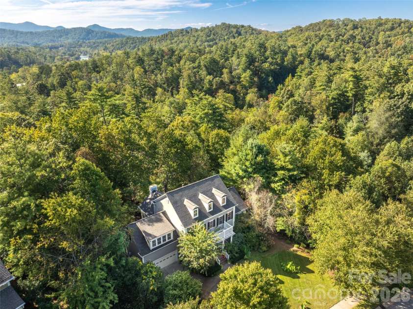 36 White Ash Drive, Asheville, NC 28803.  MLS# CAR4310417, YatesRealty ID 22580. An aerial perspective showcases this home's private, tree-lined setting with the distant mountains  offering seclusion and beauty.