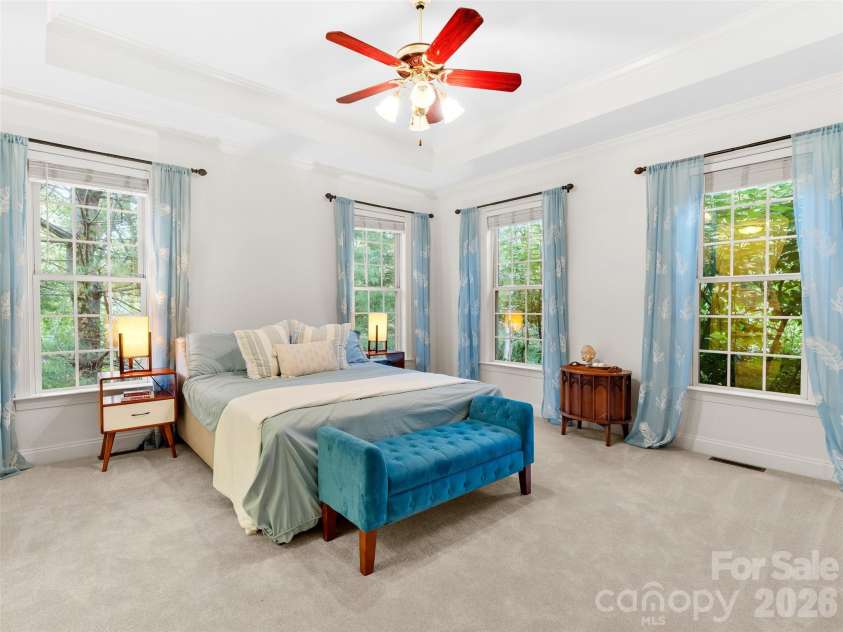 36 White Ash Drive, Asheville, NC 28803.  MLS# CAR4310417, YatesRealty ID 22580. This main-level master suite features coffered ceilings and ample windows that frame serene views of nature, creating a peaceful retreat with natural light.