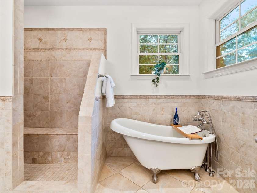 36 White Ash Drive, Asheville, NC 28803.  MLS# CAR4310417, YatesRealty ID 22580. This master bathroom features a relaxing soaking tub, a spacious open tiled shower, and windows that fill the space with natural light, creating a serene, spa-like retreat.