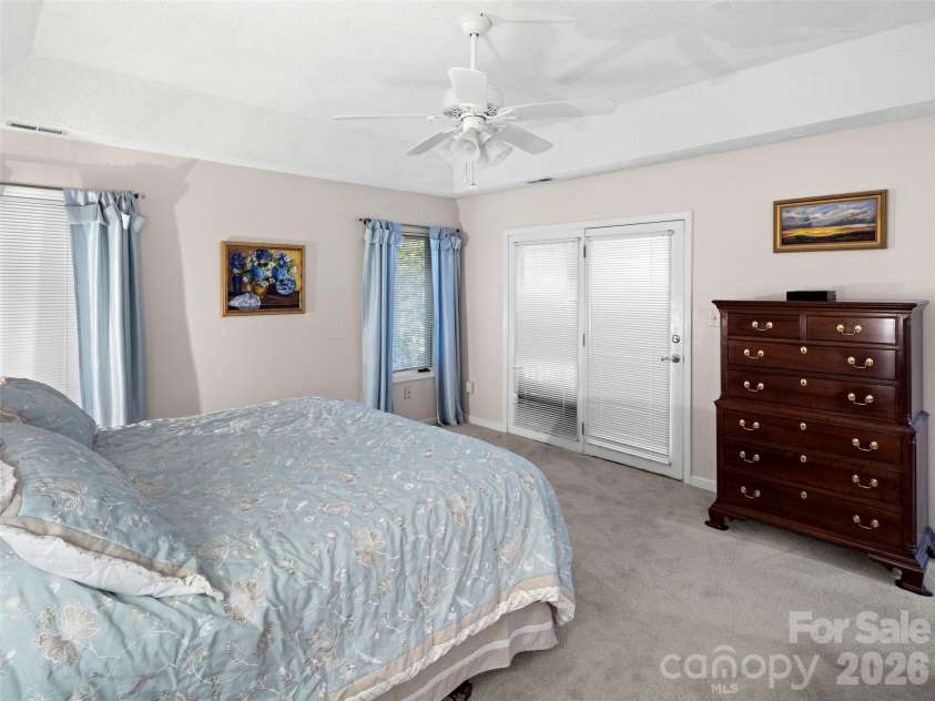 108 Galloway Drive, Asheville, NC 28803.  MLS# CAR4318726, YatesRealty ID 22581. This main-level master suite features a coffered ceiling, carpeted floors, and a private access door to the screen porch, creating a serene and stylish retreat.