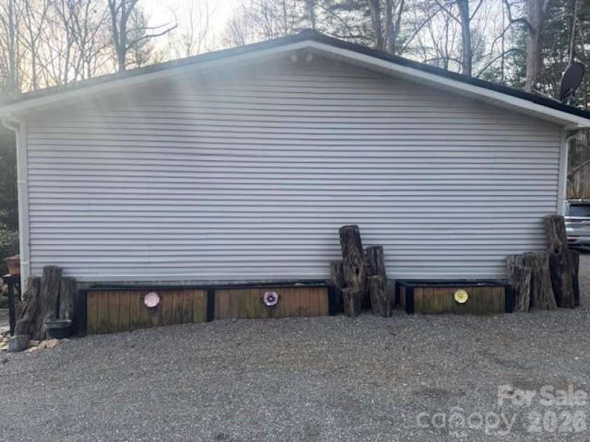 1372 Lickskillet Road, Burnsville, NC 28714.  MLS# CAR4333089, YatesRealty ID 2265. Side of house with raised garden beds.
