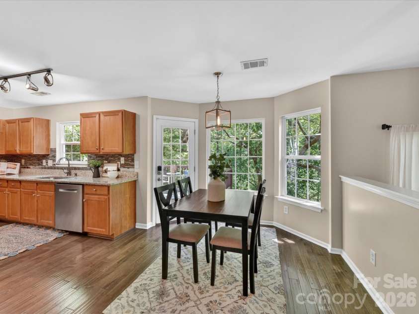 19040 Oakhurst Boulevard, Cornelius, NC 28031.  MLS# CAR4373641, YatesRealty ID 22748. Bright breakfast nook with large windows, a cozy dining area, and direct access to the deck—perfect for enjoying morning coffee with serene, tree-lined views.