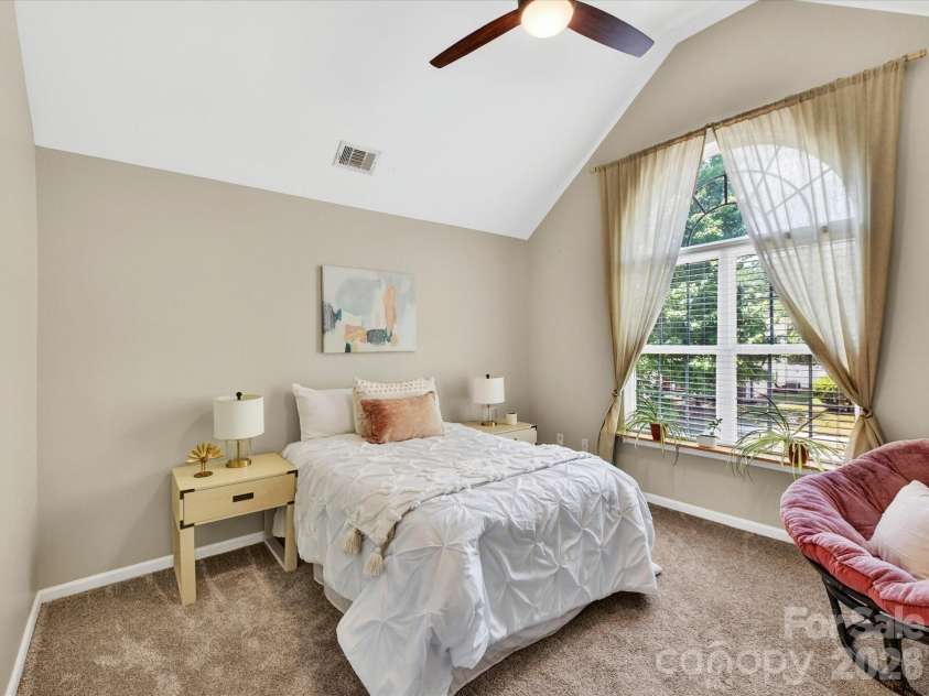 19040 Oakhurst Boulevard, Cornelius, NC 28031.  MLS# CAR4373641, YatesRealty ID 22748. Charming secondary bedroom with vaulted ceilings, abundant natural light, and a cozy layout perfect for guests or family.