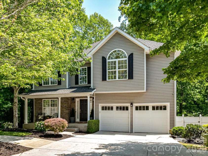 19040 Oakhurst Boulevard, Cornelius, NC 28031.  MLS# CAR4373641, YatesRealty ID 22748. Charming two-story home nestled on a beautifully landscaped, tree-lined lot featuring a welcoming front porch, classic shutters, and a spacious two-car garage.