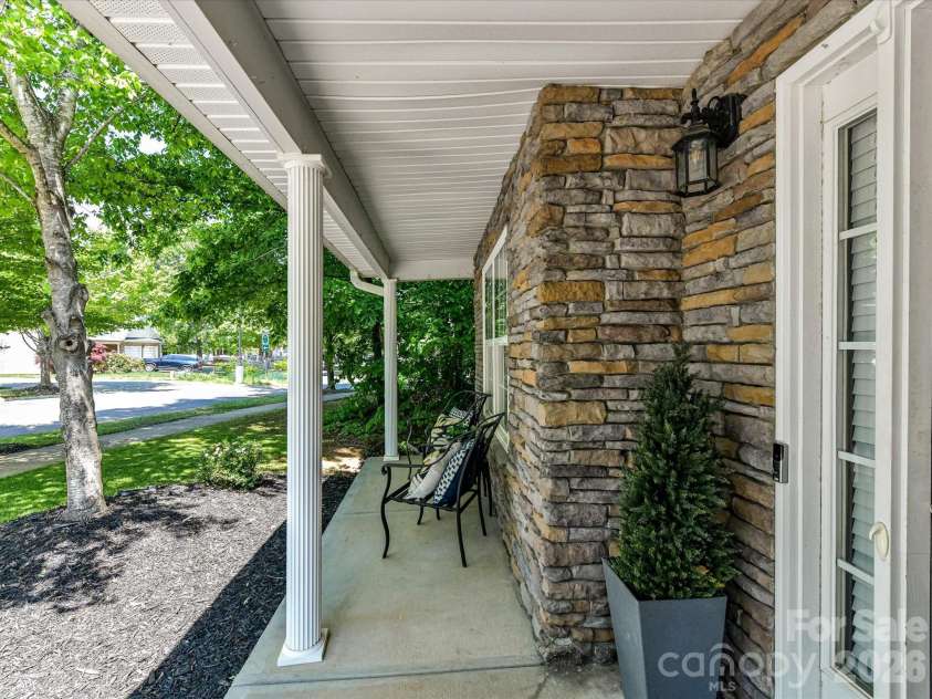 19040 Oakhurst Boulevard, Cornelius, NC 28031.  MLS# CAR4373641, YatesRealty ID 22748. Inviting covered front porch with classic columns, stone accents, and a cozy seating area—perfect for relaxing and enjoying the neighborhood views.