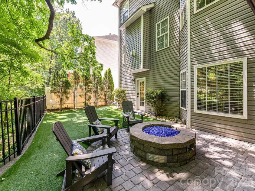 19040 Oakhurst Boulevard, Cornelius, NC 28031.  MLS# CAR4373641, YatesRealty ID 22748. Inviting patio with a custom fire pit and seating area, overlooking a private, fenced yard with lush greenery for the perfect outdoor retreat.