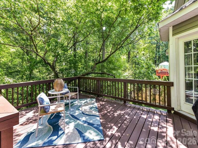 19040 Oakhurst Boulevard, Cornelius, NC 28031.  MLS# CAR4373641, YatesRealty ID 22748. Private back deck nestled among mature trees, offering a peaceful setting perfect for relaxing or entertaining outdoors.