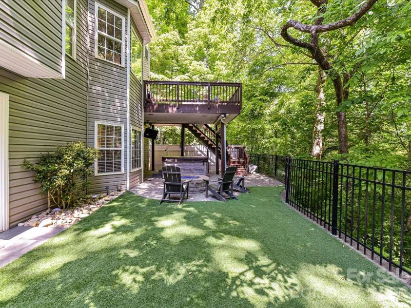 19040 Oakhurst Boulevard, Cornelius, NC 28031.  MLS# CAR4373641, YatesRealty ID 22748. Private backyard retreat featuring low-maintenance turf, a cozy fire pit seating area, and a multi-level deck surrounded by mature trees.