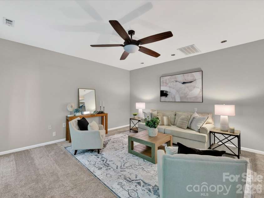 19040 Oakhurst Boulevard, Cornelius, NC 28031.  MLS# CAR4373641, YatesRealty ID 22748. Spacious family room featuring a cozy fireplace, ceiling fan, and open-concept flow to the kitchen, perfect for comfortable everyday living and entertaining.