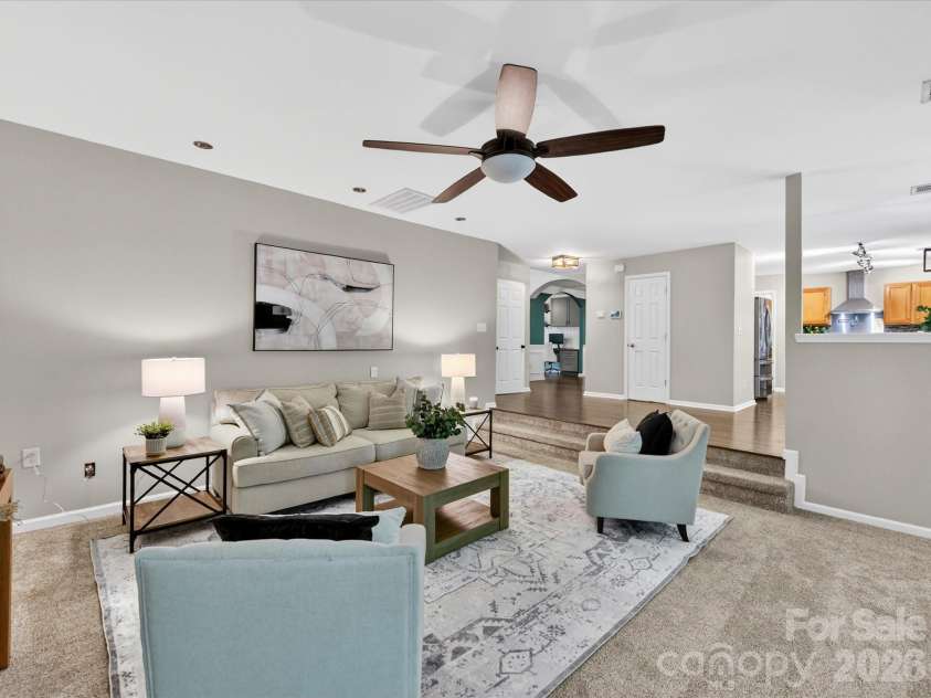 19040 Oakhurst Boulevard, Cornelius, NC 28031.  MLS# CAR4373641, YatesRealty ID 22748. Spacious family room featuring a cozy fireplace, ceiling fan, and open-concept flow to the kitchen, perfect for comfortable everyday living and entertaining.