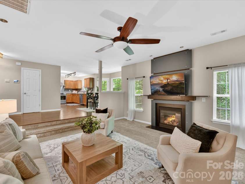 19040 Oakhurst Boulevard, Cornelius, NC 28031.  MLS# CAR4373641, YatesRealty ID 22748. Spacious family room featuring a cozy fireplace, ceiling fan, and open-concept flow to the kitchen, perfect for comfortable everyday living and entertaining.