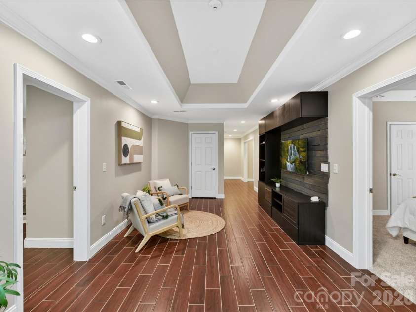 19040 Oakhurst Boulevard, Cornelius, NC 28031.  MLS# CAR4373641, YatesRealty ID 22748. Spacious recreation area featuring tray ceilings, stylish built-in media wall, and durable flooring—perfect for entertaining, relaxing, or a flexible living space.