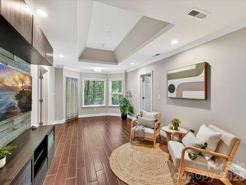 19040 Oakhurst Boulevard, Cornelius, NC 28031.  MLS# CAR4373641, YatesRealty ID 22748. Spacious recreation area featuring tray ceilings, stylish built-in media wall, and durable flooring—perfect for entertaining, relaxing, or a flexible living space.