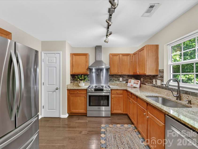 19040 Oakhurst Boulevard, Cornelius, NC 28031.  MLS# CAR4373641, YatesRealty ID 22748. Updated kitchen featuring granite countertops, stainless steel appliances, custom tile backsplash, and ample cabinetry, all highlighted by abundant natural light.