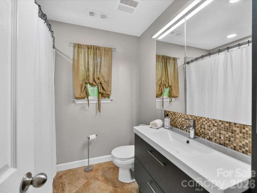 19040 Oakhurst Boulevard, Cornelius, NC 28031.  MLS# CAR4373641, YatesRealty ID 22748. Well-appointed full bath featuring a sleek vanity with modern finishes, tile flooring, and a tub/shower combination.