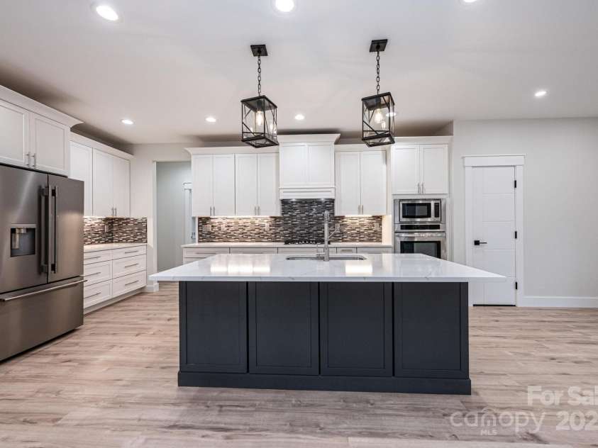 1328 33rd Avenue Drive, Hickory, NC 28601.  MLS# CAR4327859, YatesRealty ID 2279. Kitchen is Open to the Great Room. Offers a large Island with a Breakfast Bar and Sink. Quartz Countertops, Tile Backsplash, Refrigerator, Gas top Range, Microwave, Oven and Dishwasher.