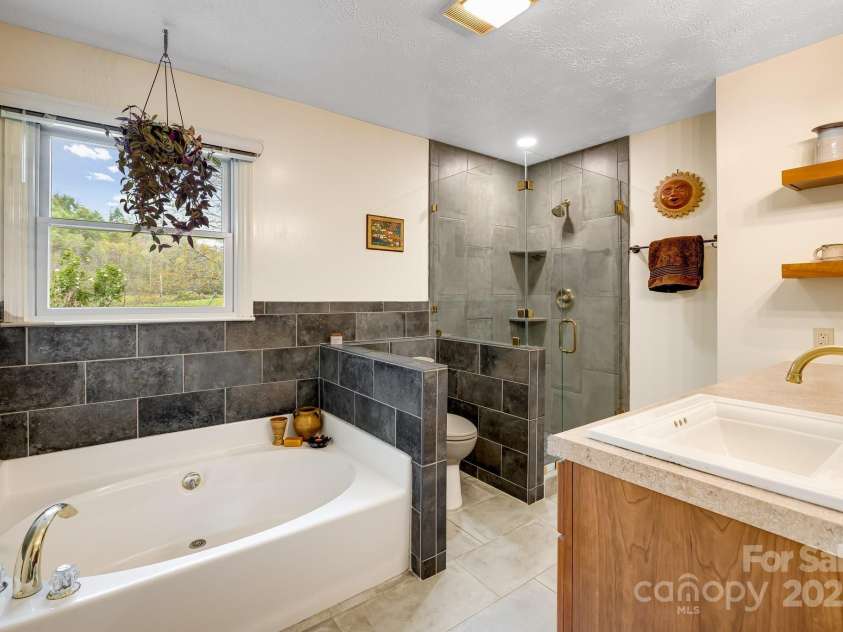 6334 Jacks Creek Road, Burnsville, NC 28714.  MLS# CAR4259403, YatesRealty ID 22798. Primary bathroom w/soaking tub & walk-in tile shower.