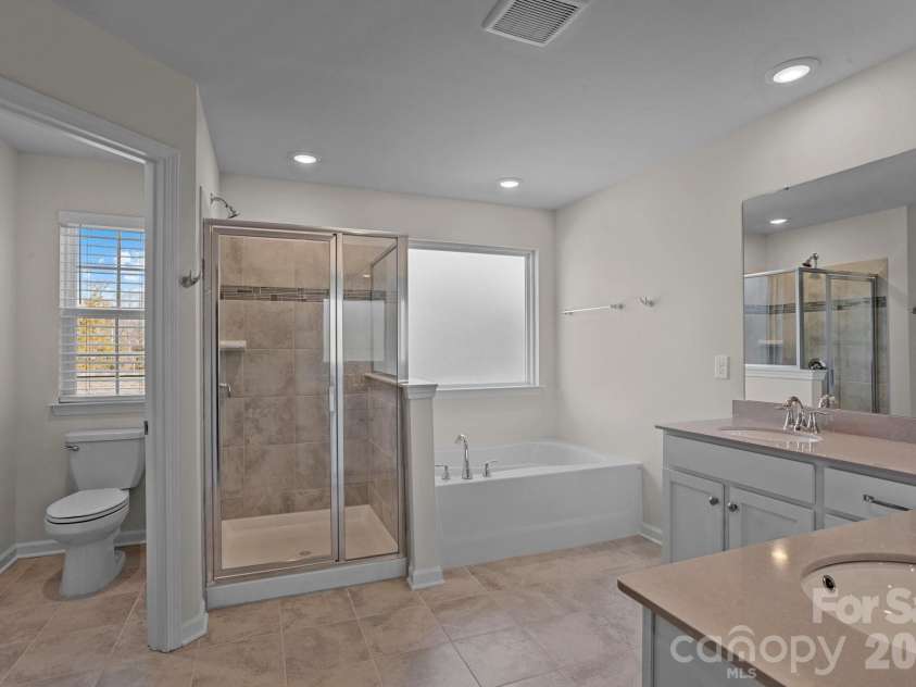 15721 White Quartz Lane, Davidson, NC 28036.  MLS# CAR4351942, YatesRealty ID 22924. Water closet, tile shower, soaking tub, and two vanities
