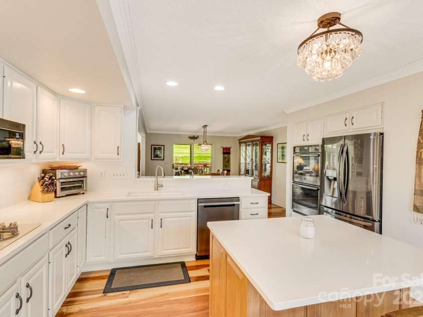118 Broadmoor Drive, Flat Rock, NC 28731.  MLS# CAR4275218, YatesRealty ID 22968. The stunning kitchen features a new island, quartz counters, white tile backsplashes, also double ovens, pantry, and gas stovetop.