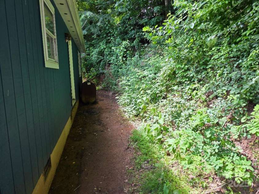 14 Yellow Brick Lane, Burnsville, NC 28714.  MLS# CAR4273450, YatesRealty ID 23082. View of the back of the house. Sellers are in the process of building a new deck/porch for the back door. The oil tank in the photo is no longer in use.
