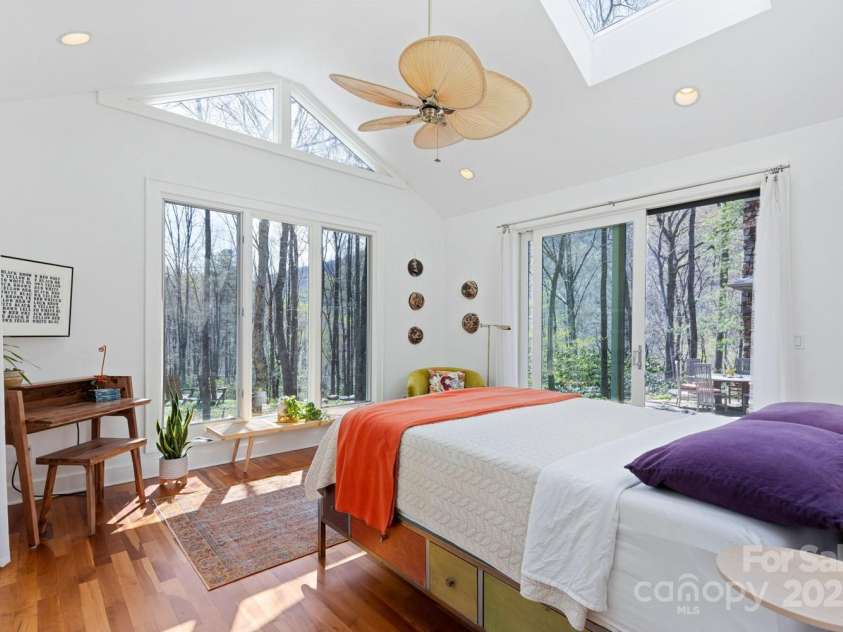 425 Bull Creek Road, Asheville, NC 28805.  MLS# CAR4251410, YatesRealty ID 23105. The guest ensuite offers a serene retreat, stunning mountain and forest views, accompanied by the soothing sounds of cascading waterfalls.