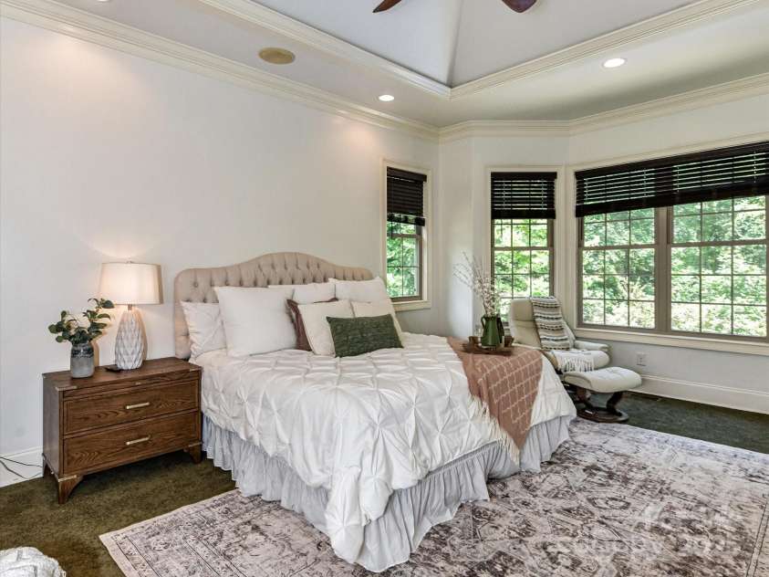 633 Elmhurst Drive, Fort Mill, SC 29715.  MLS# CAR4245784, YatesRealty ID 23352. Primary bedroom features custom walk in closet , primary bath, Tray ceiling with crown molding, large bay windows and recessed lighting create an airy, elegant vibe. The room feels serene and spacious, with earthy tones