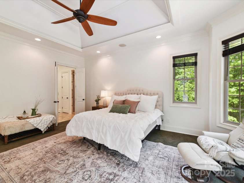 633 Elmhurst Drive, Fort Mill, SC 29715.  MLS# CAR4245784, YatesRealty ID 23352. Primary bedroom features custom walk in closet , primary bath, Tray ceiling with crown molding, large bay windows and recessed lighting create an airy, elegant vibe. The room feels serene and spacious, with earthy tones