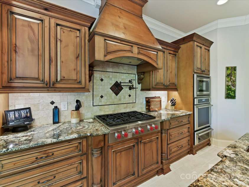 633 Elmhurst Drive, Fort Mill, SC 29715.  MLS# CAR4245784, YatesRealty ID 23352. The kitchen exudes elegance and functionality boasting a huge exotic granite breakfast bar and island, built in Wolf Stove, wall oven, 2 dishwashers, copper double farm sink & prep sink, pot filler, warming drawers, win