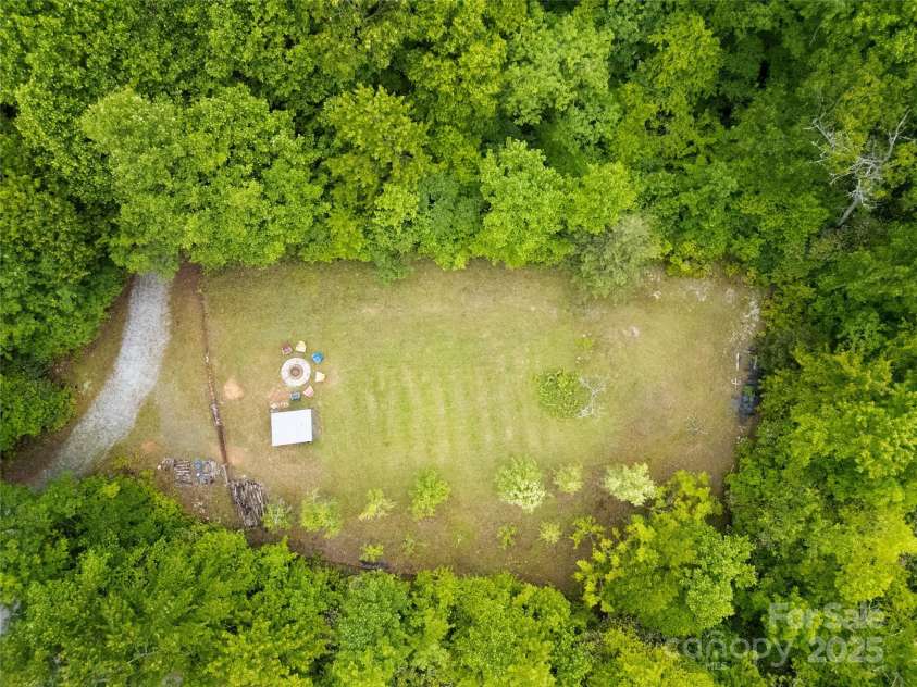 229 Hubbard Hollow Road, Rosman, NC 28772.  MLS# CAR4264936, YatesRealty ID 23454. From above you see this large open meadow, with pear trees, an old vineyard, and a great shed as well. The fire pit is a wonderful spot to watch the Indian Camp Mountain stars at night. The spring run is in the woods 