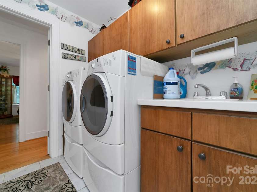 229 Hubbard Hollow Road, Rosman, NC 28772.  MLS# CAR4264936, YatesRealty ID 23454. Laundry room is full of storage cabinets and has a work sink and counter. It is a walkthrough room from the hallway to the rear sunroom.