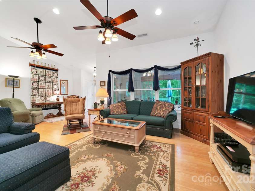 229 Hubbard Hollow Road, Rosman, NC 28772.  MLS# CAR4264936, YatesRealty ID 23454. Looking out of the living room windows through the sunroom to the front deck to the green of the front yard.