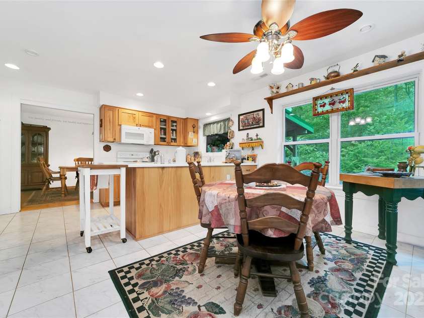 229 Hubbard Hollow Road, Rosman, NC 28772.  MLS# CAR4264936, YatesRealty ID 23454. The breakfast nook is adjacent to the kitchen and looks out to the super green foliage in the back. Refrigerator is visible on the far left.