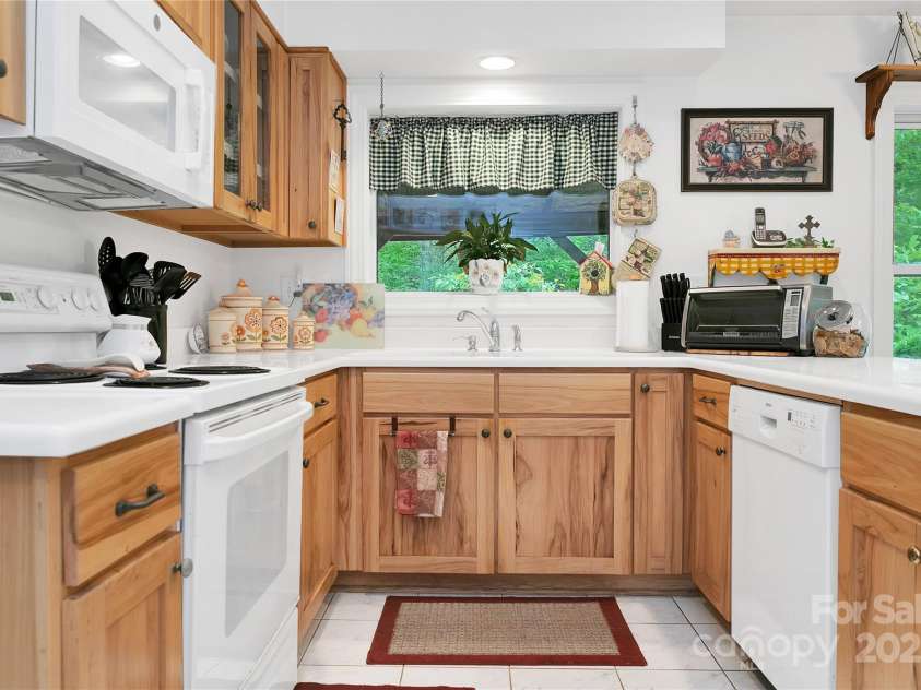 229 Hubbard Hollow Road, Rosman, NC 28772.  MLS# CAR4264936, YatesRealty ID 23454. The kitchen has a beautiful white Corian countertop, complimented by white appliances throughout. The cabinets are abundant and really work with the white.