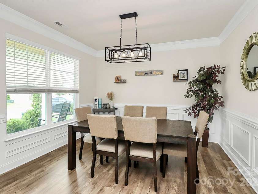 139 Suggs Mill Drive, Mooresville, NC 28115.  MLS# CAR4272116, YatesRealty ID 23610. Gather in a bright and inviting dining room featuring rich luxury vinyl plank flooring, classic wainscoting, and an abundance of natural light. This elegant space is perfect for both everyday meals and special occas