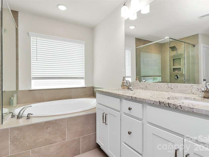 139 Suggs Mill Drive, Mooresville, NC 28115.  MLS# CAR4272116, YatesRealty ID 23610. Relax and unwind in the primary bathroom, featuring a luxurious soaker tub and a dual vanity with granite countertops—perfectly combining comfort and elegance in your private retreat.