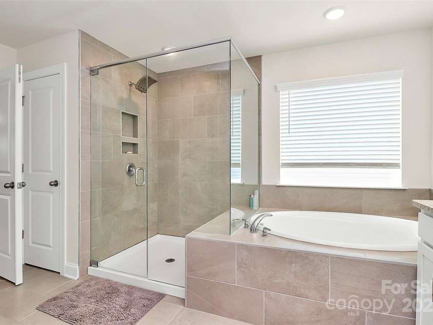 139 Suggs Mill Drive, Mooresville, NC 28115.  MLS# CAR4272116, YatesRealty ID 23610. The primary bathroom boasts a beautifully tiled shower with built-in niches for convenient storage, plus a spacious linen closet to keep essentials organized—offering both style and functionality.