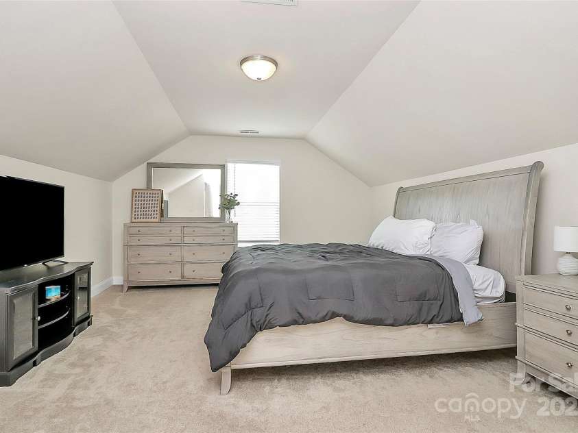 139 Suggs Mill Drive, Mooresville, NC 28115.  MLS# CAR4272116, YatesRealty ID 23610. This large third-floor bedroom/bonus room features charming, angled ceilings, creating a cozy and versatile space perfect for a guest suite, playroom, or home office.