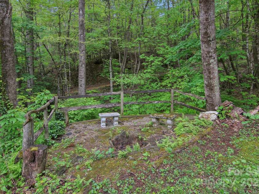 51 Atari Road, Waynesville, NC 28786.  MLS# CAR4256064, YatesRealty ID 23630. Fire Pit with the creek right below the split rail fence.  Roast marshmallows by the creek