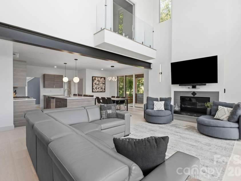 22 Lara Drive, Mills River, NC 28759.  MLS# CAR4382358, YatesRealty ID 23687. Dramatic two-story great room with soaring ceilings, oversized windows, sleek fireplace, and open-concept living spaces filled with natural light.