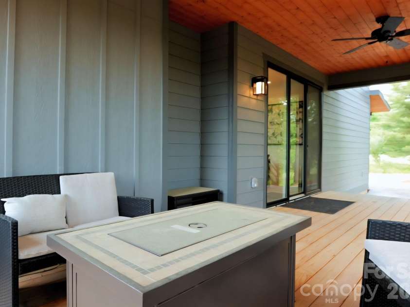 22 Lara Drive, Mills River, NC 28759.  MLS# CAR4382358, YatesRealty ID 23687. This inviting covered deck features warm wood ceilings, modern lighting, and comfortable seating, creating the perfect space for relaxing or entertaining outdoors year-round. Large sliding glass doors provide seamless indo