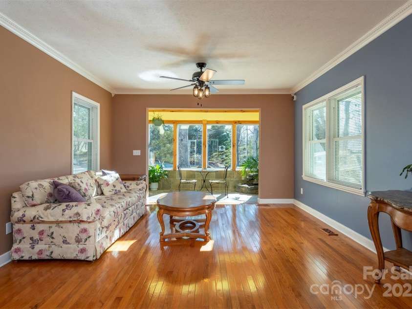 1740 Haywood Road, Hendersonville, NC 28791.  MLS# CAR4226897, YatesRealty ID 2378. Bright living room with stunning hardwood floors, seamlessly flowing into a serene solarium or versatile study.