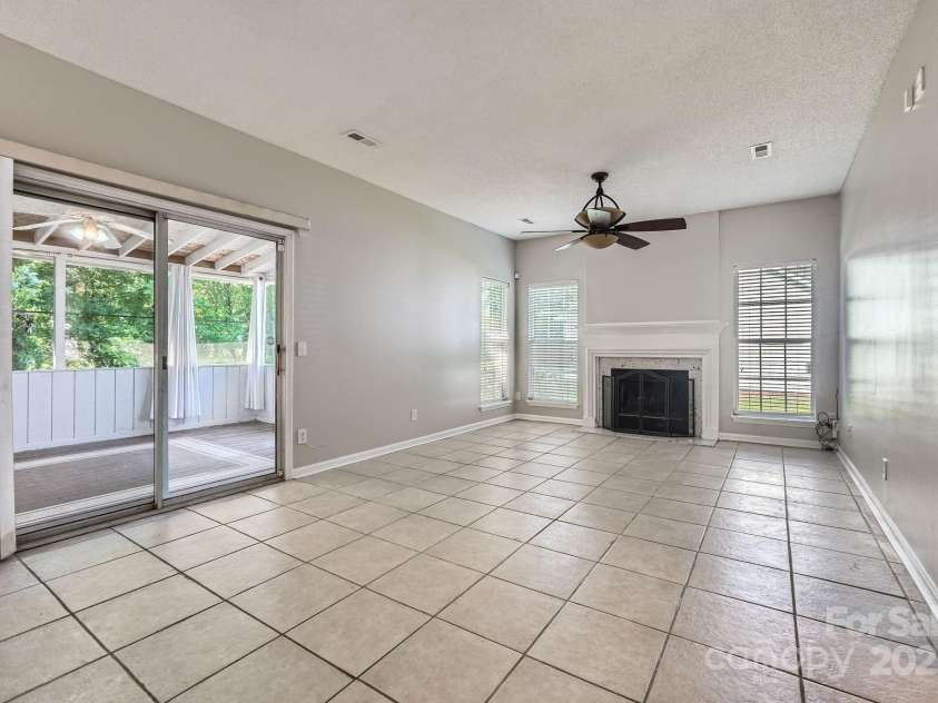 8909 Elkins Park Drive, Matthews, NC 28105.  MLS# CAR4275942, YatesRealty ID 23818. Spacious family room w/ fireplace and sliding door access to the screened porch