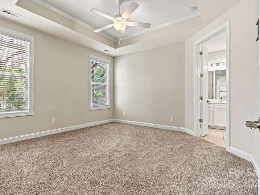 7315 Surprise Court, Charlotte, NC 28215.  MLS# CAR4276101, YatesRealty ID 23823. Spacious primary suite with tray ceiling, ceiling fan, and beautiful natural light offers neutral carpet and paint.